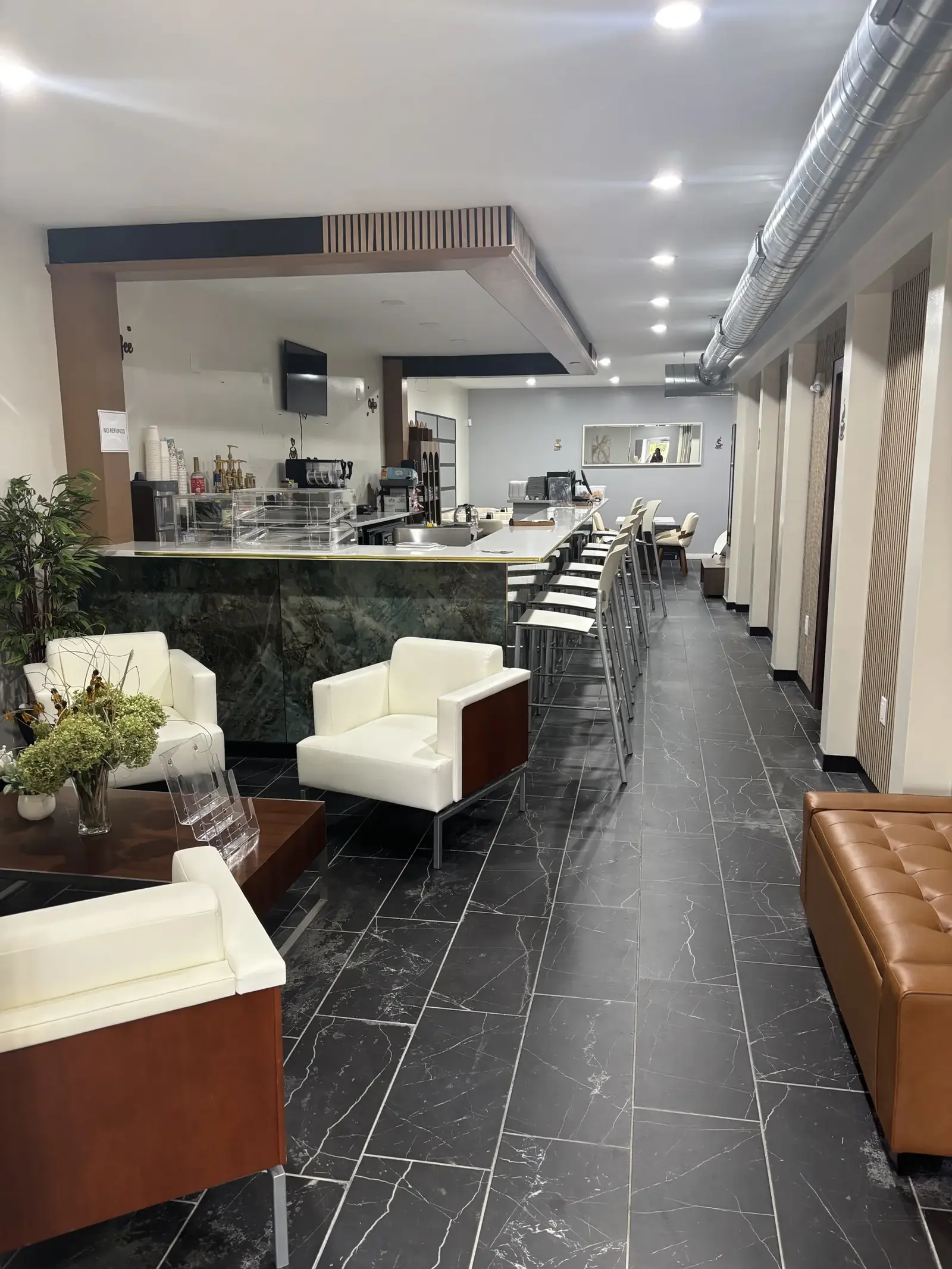 White leather lounge chairs beside Oak's green marble bar